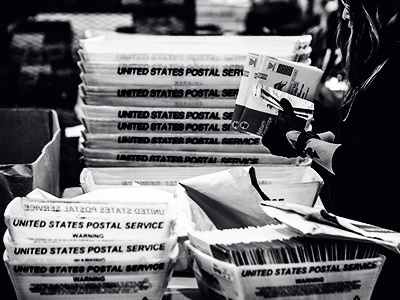 person holding ballots with postal boxes