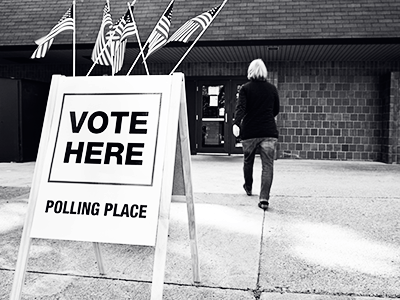 vote here sign in front of building with person walking in